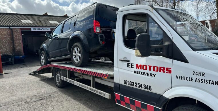 The EE Motors recovery truck loading a vehicle onto its flatbed outside the workshop