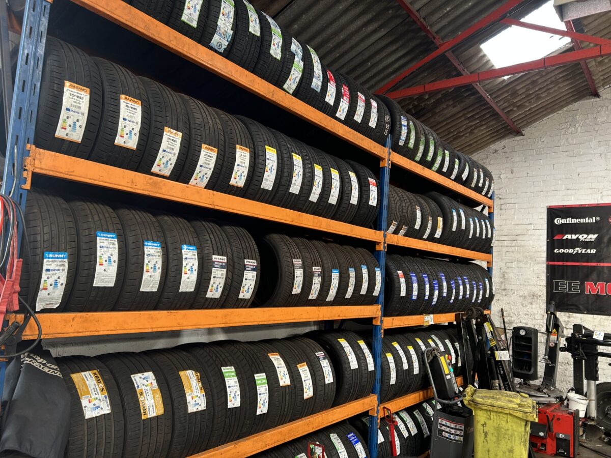 Racks of new tyres in stock at EE Motors, with Continental, Avon and Goodyear signage